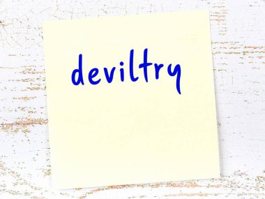 Tahta duvardaki sarı yapışkan notta el yazısıyla yazılmış şeytanlık var.