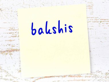 Tahta duvarda el yazısıyla yazılmış sarı yapışkan bir not var.