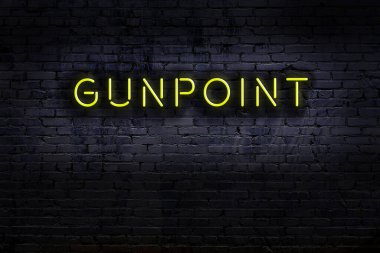 Duvara yazılı bir silah zoruyla neon levhası. Gece görünümü
