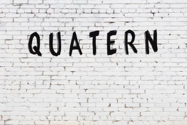 Beyaz tuğlalı duvara siyah boya ile yazılmış bir yazıt..