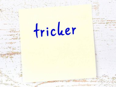 Tricker 'ı hatırlatma kavramı. Tahta duvarda üzerinde yazı olan sarı yapışkan kağıt.