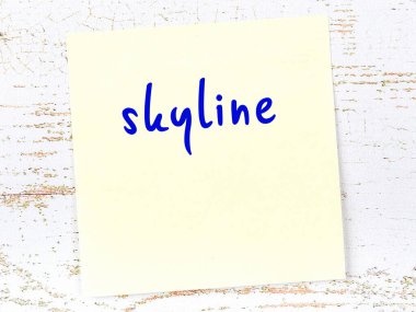 Tahta duvarda, el yazısıyla yazılmış silueti olan sarı yapışkan bir not.