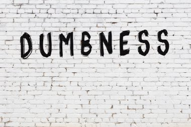 Beyaz tuğlalı duvar. Üzerinde yazı var. El yazısıyla siyah boya.