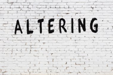 Beyaz tuğla duvarda siyah boya ile yazılmış yazılar..