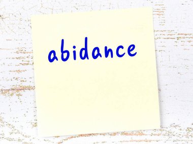 Tahta duvarda el yazısıyla yazılmış sarı yapışkan bir not var.