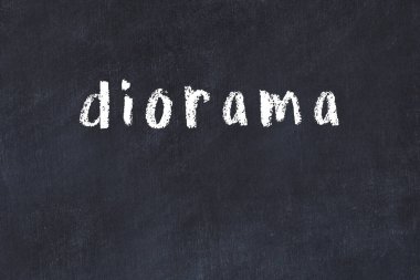 Tebeşir el yazısıyla yazılmış diyorama siyah masada.