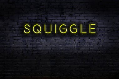 Üzerinde yazı olan neon levhası tuğla duvara karalanmış. Gece görünümü
