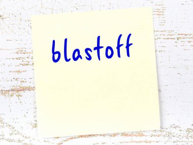 Tahta duvarda el yazısıyla yazılmış sarı yapışkan bir not var.