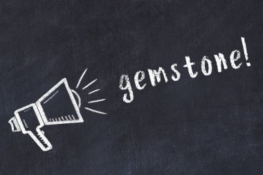 Hoparlörün tebeşir çizimi ve siyah masanın üzerine el yazısıyla yazılmış değerli taş.