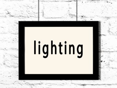 Siyah ahşap çerçeve beyaz tuğla duvarda yazılı aydınlatma asılı. 