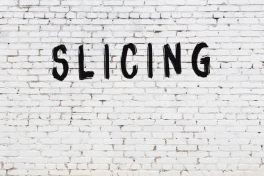 Yazı, beyaz tuğla duvara siyah boya ile yazılmış..