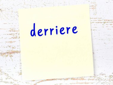 Derriere 'i hatırlatma kavramı. Tahta duvarda üzerinde yazı olan sarı yapışkan kağıt.