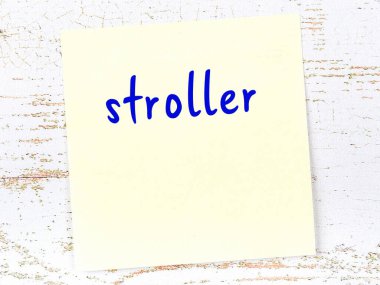 Tahta duvardaki sarı yapışkan notta el yazısıyla yazılmış bebek arabası var.