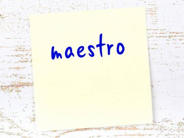 Tahta duvardaki sarı yapışkan notta el yazısıyla yazılmış maestro.