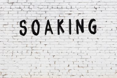 Yazı, beyaz tuğla duvara siyah boya ile yazılmış..