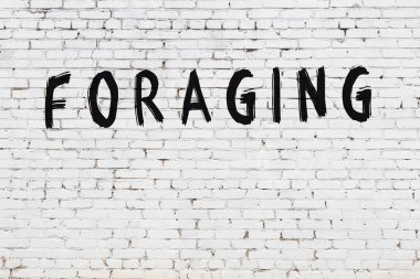 Yazı, beyaz tuğla duvarda siyah boya ile yazılmış..