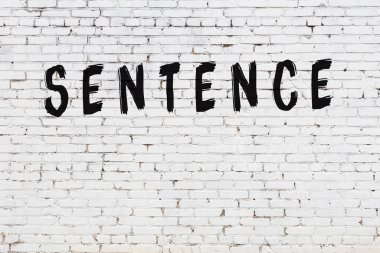 Üzerinde siyah boya bulunan beyaz tuğla bir duvar.