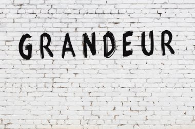 Yazılı beyaz tuğla duvar. Siyah boyalı görkemli bir el yazısı.