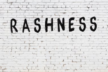 Beyaz tuğladan bir duvar. Üstünde de siyah boya ve el yazısı var.