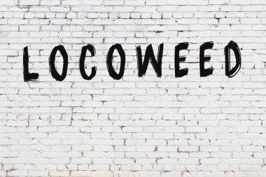 Siyah boyalı el yazısıyla yazılmış lokomotifli beyaz tuğla bir duvar.