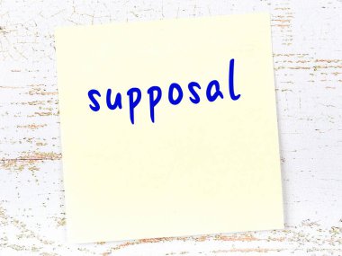 Tahta duvarda el yazısıyla yazılmış sarı yapışkan bir not var.