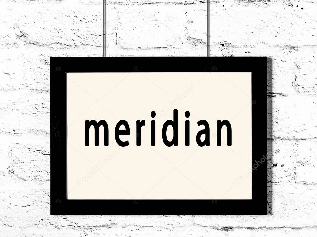 Black wooden frame with inscription meridian hanging on white brick wall 
