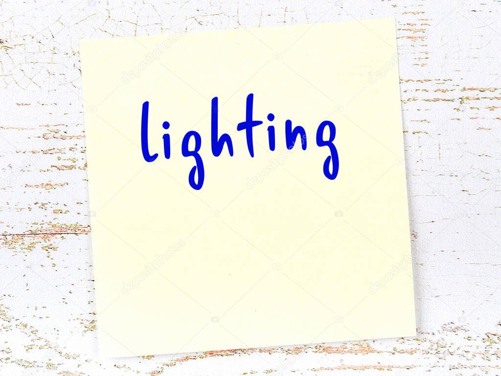 Concept of reminder about lighting. Yellow sticky sheet of paper on wooden wall with inscription