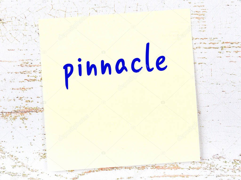 Concept of reminder about pinnacle. Yellow sticky sheet of paper on wooden wall with inscription