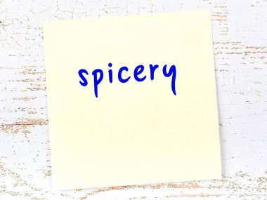 Tahta duvardaki sarı yapışkan notta el yazısı baharat var.