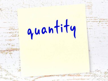 Miktarı hatırlatma kavramı. Tahta duvarda üzerinde yazı olan sarı yapışkan kağıt.