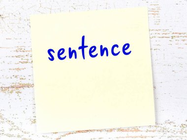 Tahta duvarda el yazısıyla yazılmış sarı yapışkan bir not var.