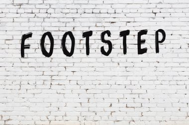 Üzerinde siyah boya ile el yazısı olan beyaz tuğla bir duvar.