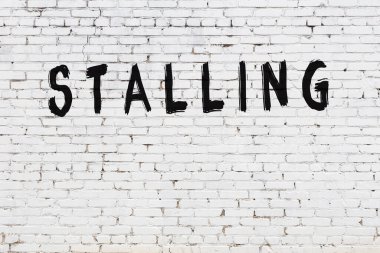 Yazı, beyaz tuğla duvara siyah boya ile yazılmış..