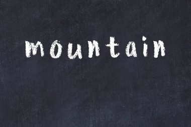 Tebeşir elle yazılmış yazı dağını siyah masanın üzerine.