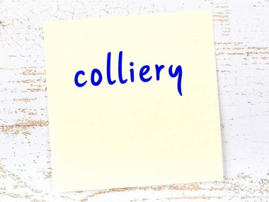 Tahta duvardaki sarı yapışkan notta el yazısı kömür madeni var.