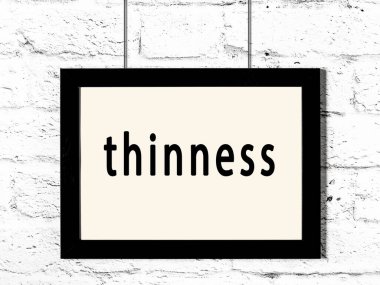 Siyah ahşap çerçeve, beyaz tuğla duvarda ince yazılar asılı. 