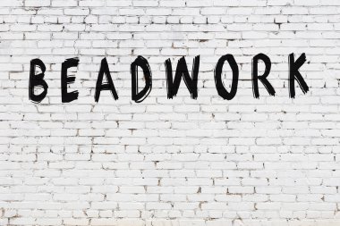 Beyaz tuğla duvara siyah boya ile yazılmış boncuk yazıları..