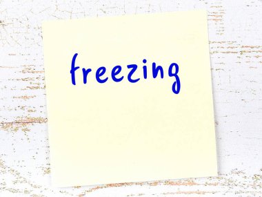 Tahta duvardaki sarı yapışkan notta elle yazılmış yazılar donduruyor.