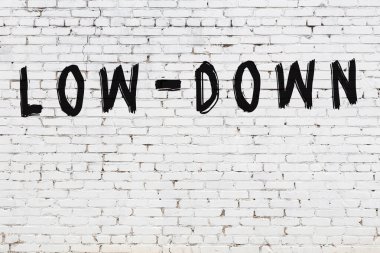 Beyaz tuğla duvarda siyah boyayla yazılmış..