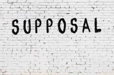 Yazı, beyaz tuğla duvara siyah boya ile yazılmış..