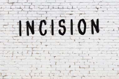 Yazı kesiği beyaz tuğla duvara siyah boya ile yazılmış..