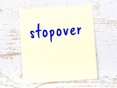 Tahta duvarda el yazısıyla yazılmış sarı yapışkan bir not var.