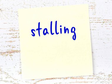 Oyalama hakkında hatırlatma kavramı. Tahta duvarda üzerinde yazı olan sarı yapışkan kağıt.