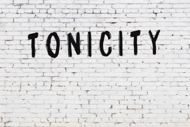Beyaz tuğlalı duvar, tonikle yazılmış, siyah boyalı.
