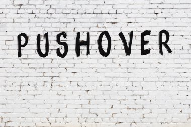 Beyaz tuğlalı duvara siyah boya ile yazılmış bir yazı..