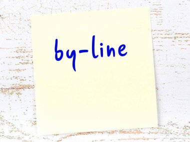 Tahta duvarda el yazısıyla yazılmış sarı yapışkan bir not var.