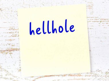 Tahta duvardaki sarı yapışkan notta el yazısıyla yazılmış cehennem deliği var.