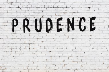 Beyaz tuğla duvarda siyah boyayla yazılmış bir yazıt..