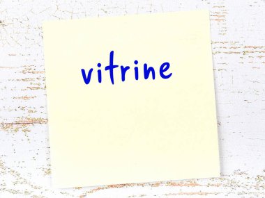 Tahta duvardaki sarı yapışkan notta el yazısıyla yazılmış vitrin var.