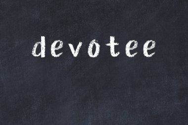 Tebeşir el yazısıyla yazılmış bir yazı, siyah masanın üzerinde.